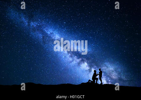 Voie lactée. Paysage de nuit avec des silhouettes d'un homme faire de demande en mariage à sa petite amie et ciel étoilé. Silhouette de lo Banque D'Images