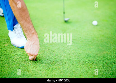 Joueur de golf réparation divot sur une surface d'herbe verte Banque D'Images