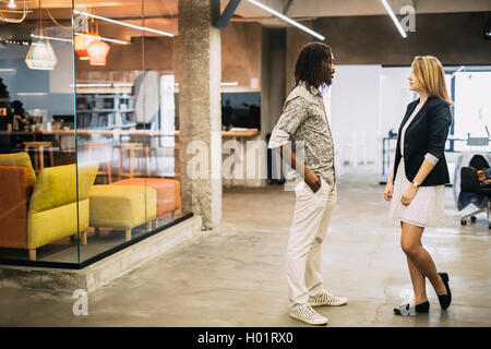 Colleagues talking in a modern office avant de s'asseoir à leur bureau. Banque D'Images