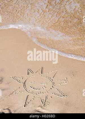 Doigt dessiné soleil sur plage de sable Banque D'Images