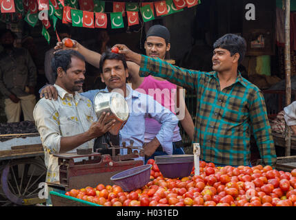 MUMBAI, INDE - 12 janvier 2015 : les vendeurs de rue se moquent de l'autre. Vendeur met les tomates dans un sac. Banque D'Images