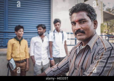 KAMALAPURAM, INDE - 02 février 2015 : Indian man sur moto à côté de trois jeunes hommes sur la clôture des marchés à Hampi. Post-traités Banque D'Images