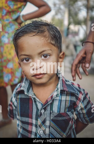 HAMPI, INDE - 31 janvier 2015 : jeune Indien en chemise colorée avec les membres de la famille en arrière-plan. Post-traités avec grain, textu Banque D'Images