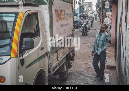 MUMBAI, INDE - 12 janvier 2015 : Indian man stands près du chariot à Dharavi slum et entretiens sur téléphone cellulaire. Post-traités avec gra Banque D'Images