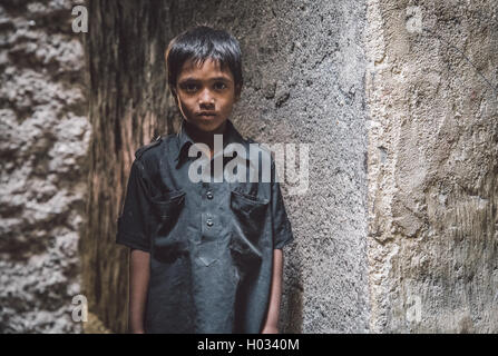 MUMBAI, INDE - 12 janvier 2015 : jeune garçon indien du bidonville de Dharavi est vide dans la rue étroite. Post-traités avec grain, te Banque D'Images