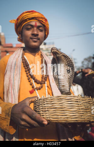 VARANASI, INDE - 23 février 2015 : jeune Indien habillés en vêtements religieux détient dans panier cobra. Post-traités avec grain, Banque D'Images