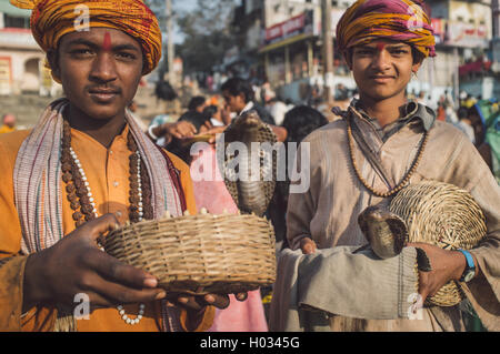 VARANASI, INDE - 23 février 2015 : deux garçons indiens habillés en vêtements religieux tenir cobras dans des paniers. Post-traités avec Banque D'Images