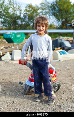 ZAGREB, CROATIE - 21 octobre 2013 : cute little boy Roms posant avec petit vélo en face du dépotoir de la rue. Banque D'Images