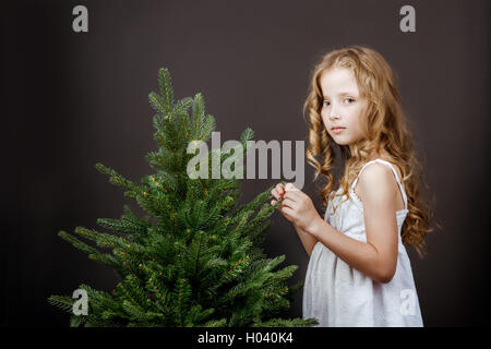 Jolie petite jeune fille se tient près de l'arbre concept Banque D'Images