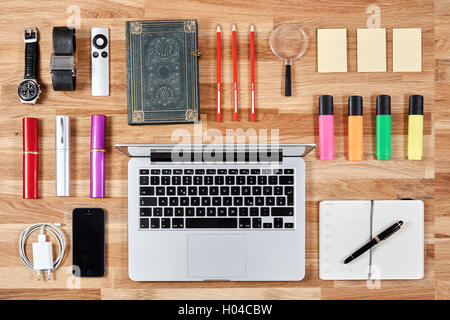 Haut Vue de dessus de bureau avec ordinateur portable et des crayons et des postits, un livre, un ordinateur portable, de montres et d'un smartphone afin Banque D'Images
