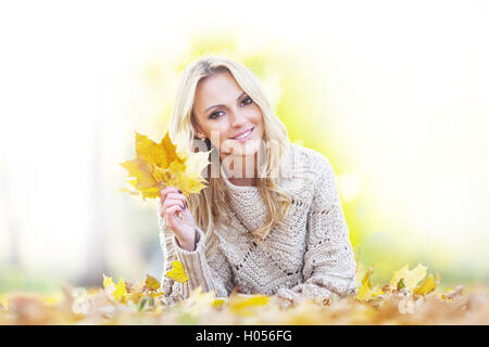 Happy woman se trouve sur des feuilles sèches à l'automne au parc journée ensoleillée Banque D'Images