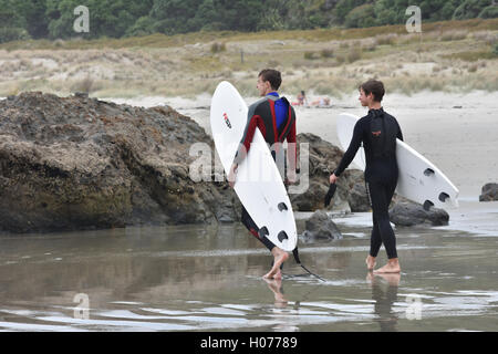 Deux surfeurs mâles en combinaison transportant des planches de surf Banque D'Images