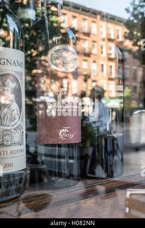 Les bouteilles de vin rouge choix lueur en vitrine du restaurant italien le verre reflète le zonage du 19ème siècle protégé des logements en brique Banque D'Images