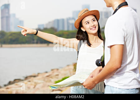 Jeune couple de touristes asiatiques qui tentent de localiser un endroit à l'aide d'un plan paysage Banque D'Images