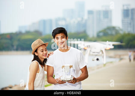 Young Asian couple travaillant un bourdon dans un parc de la ville Banque D'Images