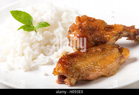 Ailes de poulet grillé avec du riz sur une plaque blanche Banque D'Images