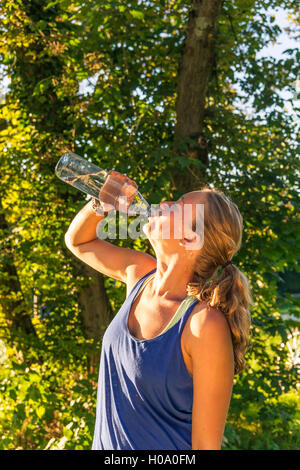 Jeune femme dans les vêtements de sport eau potable dans une bouteille, Bavière, Allemagne Banque D'Images