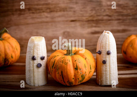 Trois citrouilles et fantômes faits avec banane et chocolat pour l'halloween sur du bois Banque D'Images