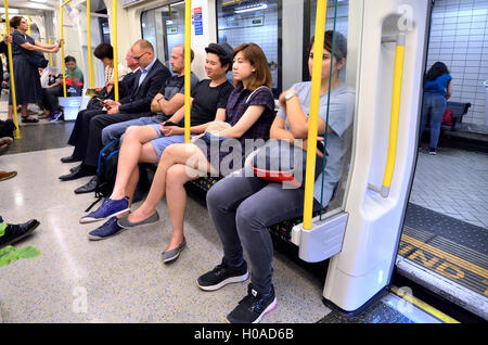 Londres, Angleterre, Royaume-Uni. Les gens dans le transport d'une London Underground tube train. Jeune couple chinois Banque D'Images