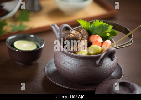 Pot noir de crevettes et de champignons et d'herbes sur la table Banque D'Images