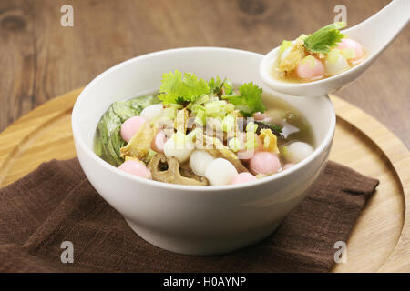 Soupe de riz spécial ball et champignons en plaque blanche sur plateau en bois Banque D'Images