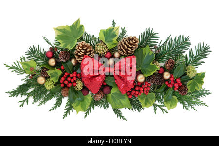 Décoration de Noël avec red bow, décorations babiole, houx, lierre, pommes de pin d'or, de cèdre et de cyprès feuille sapin branches over white Banque D'Images