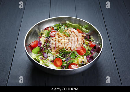 Salade de pâtes avec Chichen spaghetti, la tomate et les herbes dans un bol Banque D'Images