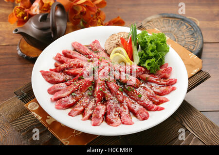 Tranches de boeuf assaisonné sur plaque blanche avec du citron, champignons et salade Banque D'Images