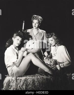 Trois femmes dans une grange carving pumpkins at night Banque D'Images