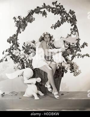 Femme assise dans le panier de Pâques géant avec le lapin jouet Banque D'Images