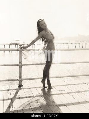 Femme en maillot de bain sur la pointe des pieds posing on pier Banque D'Images