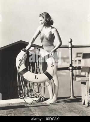 Woman on pier tenant un conservateur de vie Banque D'Images