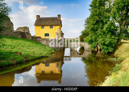 Une jolie chaumière construite sur les ruines d'un château médiéval entouré de douves à Stogursey à Somerset Banque D'Images