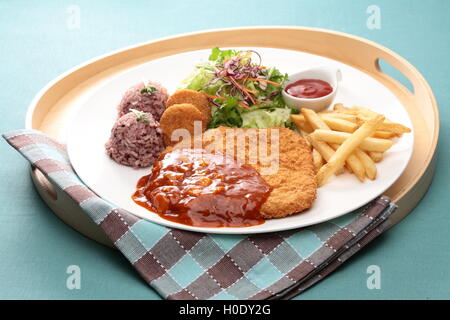 Escalopes de porc avec cripsy assortis de pommes de terre, riz, salade et la sauce chili sur plateau en bois Banque D'Images