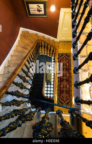 Un vertigineux vue vers le bas de l'escalier de l'étage supérieur d'une grande maison ancienne. Banque D'Images