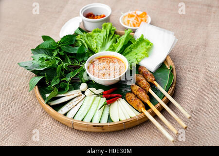 Rouleau de porc fermenté vietnamiens ou nem de Hue avec laitue, les herbes et la sauce chili sur plateau en bambou rouleau de porc fermenté vietnamiens Banque D'Images