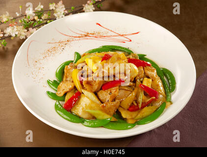 Pois verts sautés au poulet et piment sur plaque blanche dans le Banque D'Images