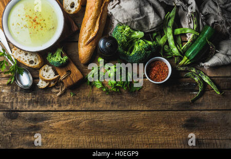 La courgette, le brocoli et les haricots verts dans un bol de soupe à la crème aux épices et la baguette fraîche sur fond de bois rustique. Vue de dessus, co Banque D'Images