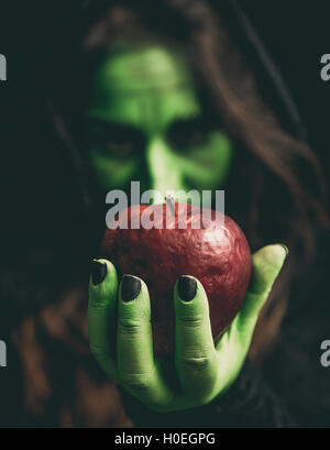 Sorcière vert main tenant une pomme rouge pourri. Profondeur de champ. Banque D'Images