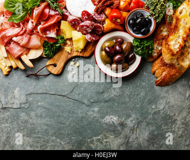 Ingrédients alimentaires italien de fond avec jambon, salami, parmesan, olives, bâtonnets de pain sur ardoise en pierre Banque D'Images