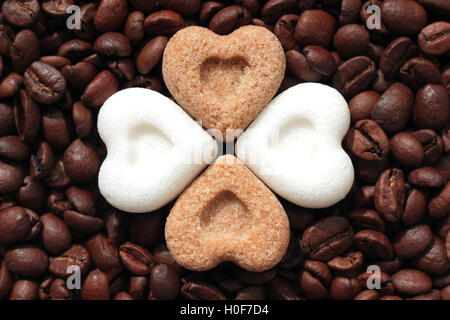 Coeurs de sucre brun et blanc couché sur les grains de café torréfié Banque D'Images