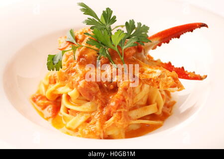 Pince de crabe avec sauce et pâtes nouilles fines herbes cumin sur plat blanc Banque D'Images