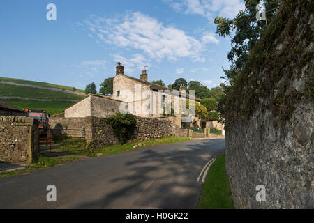 Vue vers le haut un chemin de campagne vers une maison en pierre traditionnelle, à flanc et les champs derrière - Kettlewell, Yorkshire Dales, GB. Banque D'Images