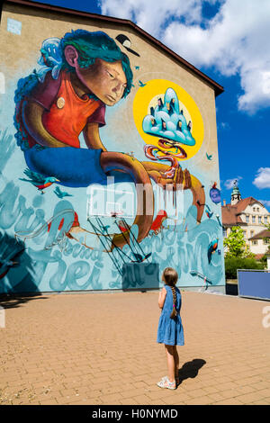 Un motif coloré graffity avec comic est peint dans un mur de la maison, une petite fille est à la recherche jusqu'à elle, Würzburg, Bavière, Allemagne Banque D'Images