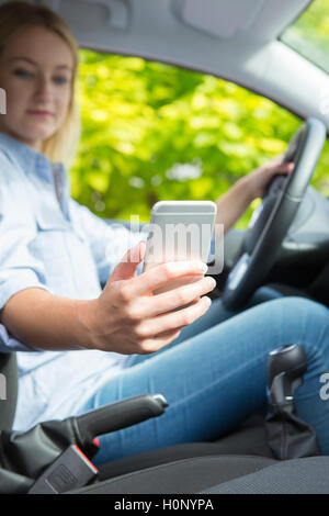 Woman in Car SMS sur téléphone mobile pendant la conduite Banque D'Images