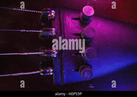 Studio de la composition d'un vieux violon poussiéreux, bleu et violet à partir de l'éclairage de côté, vue rapprochée sur fine tuners et des chaînes. Banque D'Images