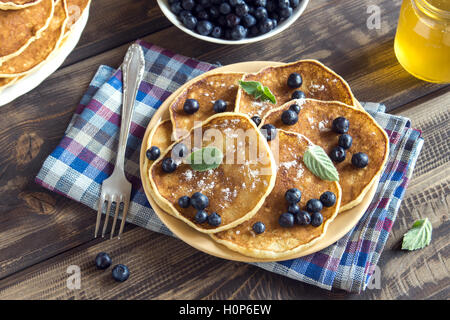 Des crêpes sur la plaque avec des bleuets, de la menthe et du miel pour le petit déjeuner fait maison - l'alimentation végétarienne saine Banque D'Images