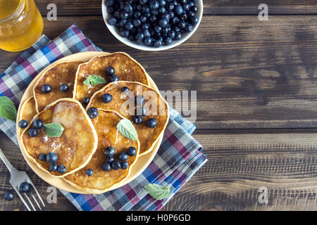 Des crêpes sur la plaque avec des bleuets, de la menthe et du miel pour le petit déjeuner fait maison - l'alimentation végétarienne saine Banque D'Images