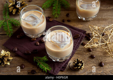 Irish Cream Liqueur de café avec de la glace, et des ornements de décoration de Noël sur fond de bois rustique - boisson festive fait maison Banque D'Images