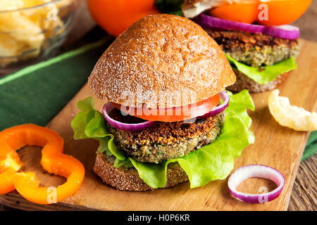 Burger de lentilles végétarien avec légumes sur planche à découper en bois - savoureux en-cas sains végétariens (nourriture, le déjeuner) Banque D'Images
